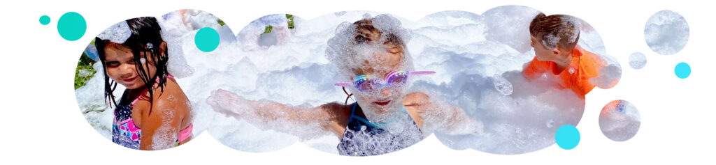 PreK students wearing goggles and bathing suits, standing in a pile of foam up to their shoulders